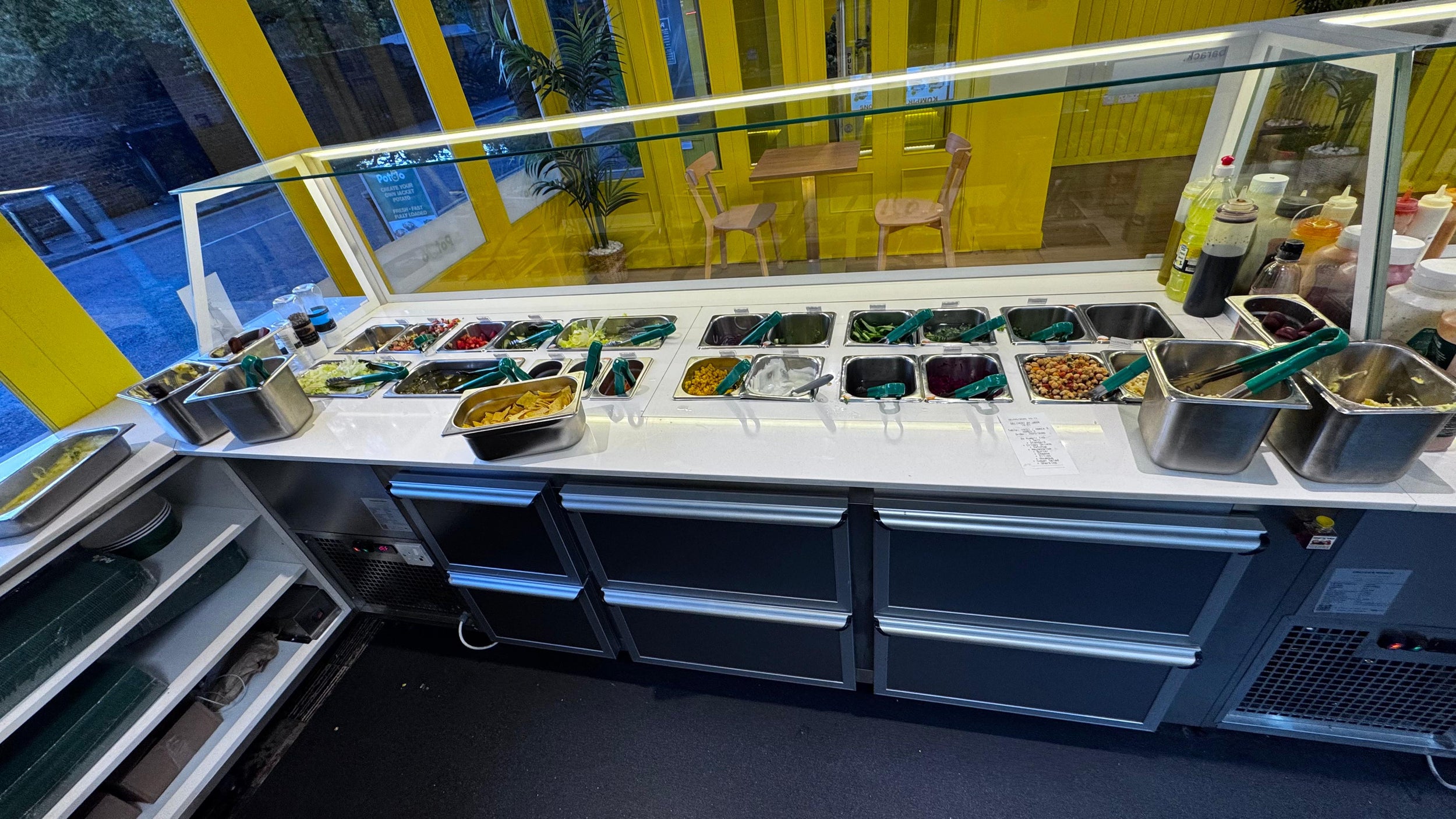 Food counter with various dishes in containers at a food court.